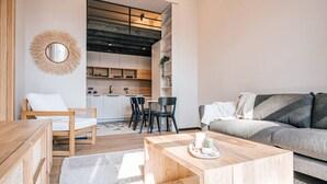 Una sala de estar moderna con una mesa de centro de madera, un sofá gris y un comedor con sillas negras.