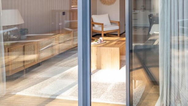 Un interior moderno con un vidrio que da a una terraza de madera.