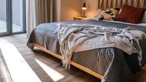 Un dormitorio con cama, mesita de noche, lámpara y vistas amplias a través de un ventanal.