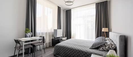 Una habitación de hotel moderna con una cama, un escritorio, una silla, un televisor y una lámpara.