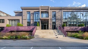 Un edificio moderno con fachada simétrica, ventanas amplias y una entrada central con escaleras.