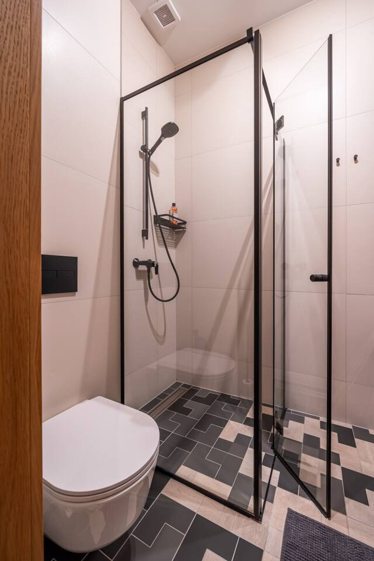 Et moderne badeværelse med en brusekabine med glasvægge, et toilet og et flisegulv.
