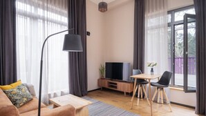 Una sala de estar moderna con sofá, mesa de centro, televisor y comedor.