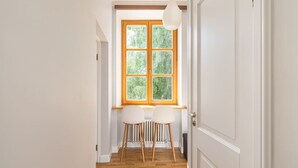 Un passadís amb terra de fusta, una finestra que dona a глебе i una porta blanca.