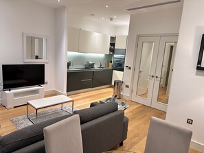 Una sala de estar moderna con un televisor de pantalla plana, un sofá gris y una mesa de centro.