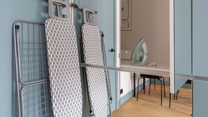 A room with a wooden floor, a mirror, and ironing boards. - Trendy beach-front 1-bedroom apartment in Dzintari (Jūrmala)