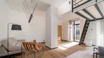 A modern living space with a loft area, a sofa, a chair, and a floor lamp.