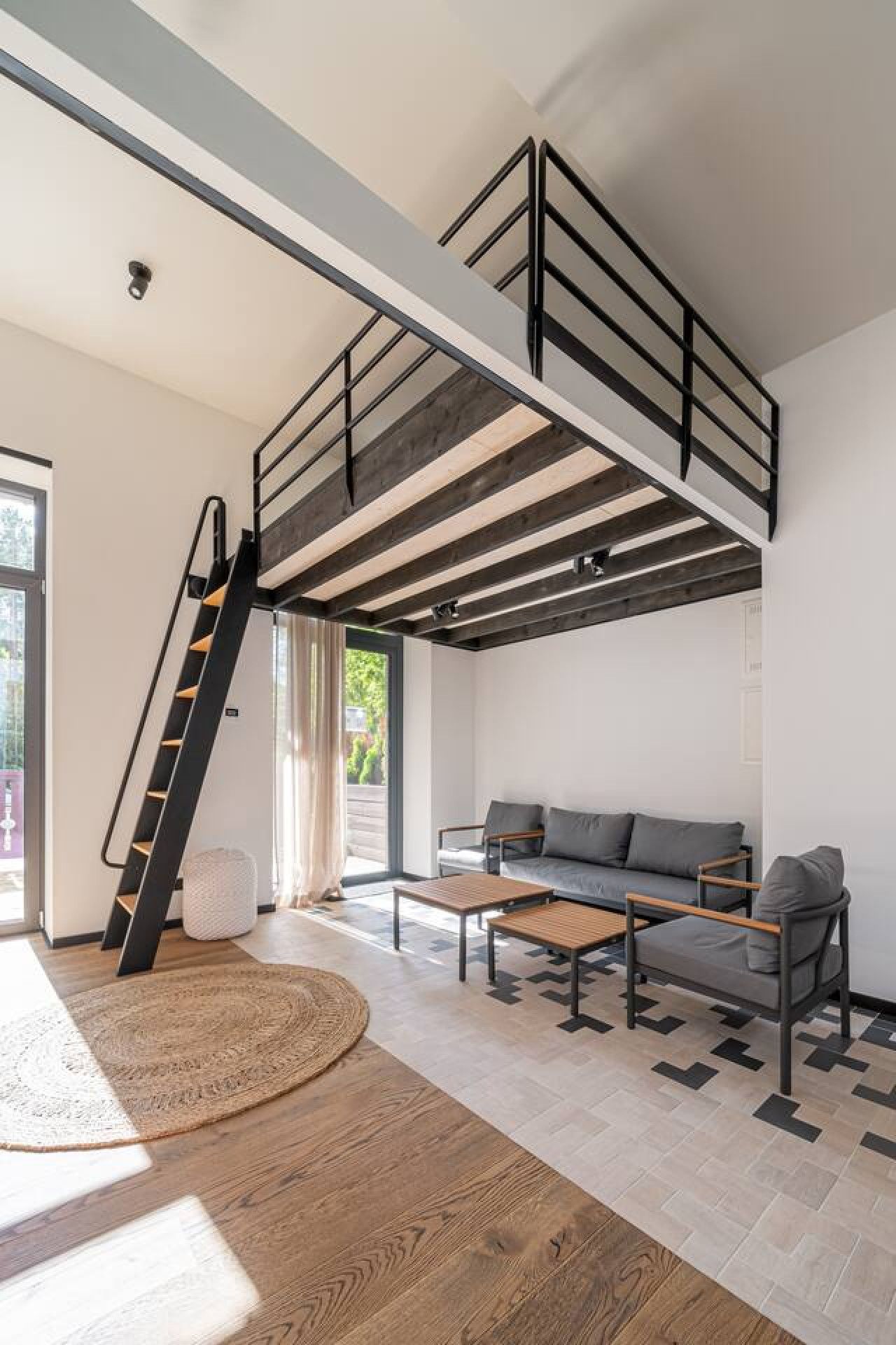 A modern loft with a loft bed, a staircase, a sofa, and a coffee table.