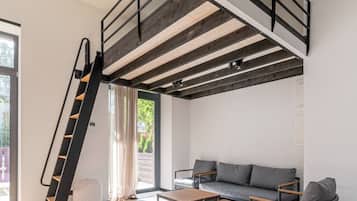 A modern loft with a loft bed, a staircase, a sofa, and a coffee table.