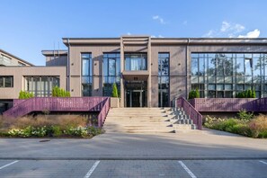 Un edificio moderno con fachada simétrica, ventanas amplias y una entrada central con escaleras.
