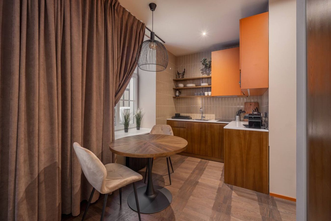 A compact kitchen with wooden cabinets, a round dining table, and two chairs.