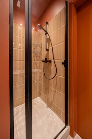 A glass-enclosed shower with beige tiles and a black frame. - Stylish old town apartment (Rīga)