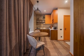 A modern kitchen with wooden cabinets, a round dining table, and a pendant light. - Stylish old town apartment (Rīga)