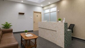 A reception area with a reception desk, a brown leather couch, a wooden table with a plant, and a door labeled 'RECEPTION'.
