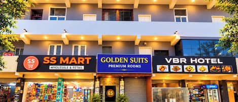 A multi-story building with a ground floor featuring a SS Mart, a Golden Suits Premium Rooms, and a VBR Hotel.