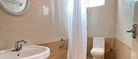 Un baño con lavamanos, inodoro y cortina de ducha.