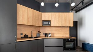 Una cocina moderna con armarios oscuros, una encimera de madera, microondas, hervidor y horno.