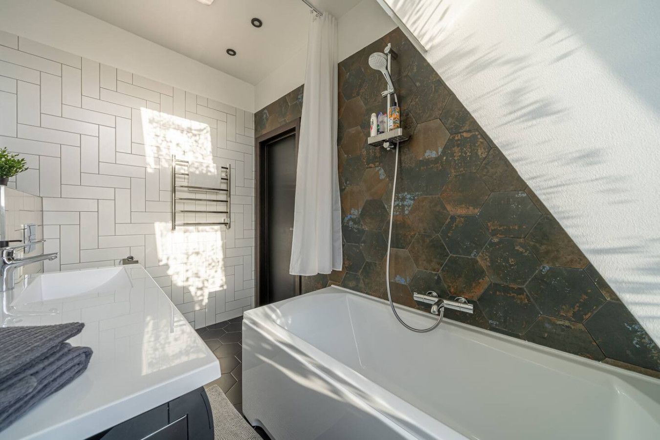 A modern bathroom with a white vanity, a bathtub, and a shower area with a stone wall.