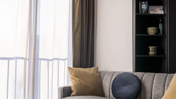Una sala de estar moderna con un sofá gris, una mesa de centro redonda negra y una estantería junto a la pared.