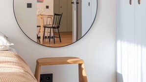 Una camera da letto con un letto, una sedia in legno, uno specchio rotondo e un armadio.