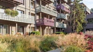 Un edificio residenziale a più piani con balconi, un vialetto lastricato e vegetazione circostante.