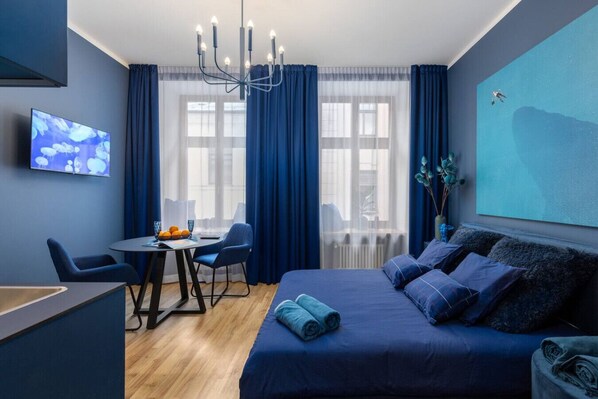 Une chambre d’hôtel moderne dotée d’un grand lit, d’un bureau avec une chaise, d’une télévision et offrant une vue sur la ville grâce à de grandes fenêtres.