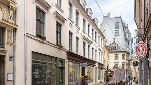 A cobblestone street lined with historic buildings, some with storefronts and signage. - Sojourn in Old Town studio apartment (Riga)