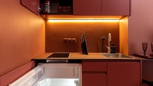 A compact kitchen with a built-in refrigerator, a sink, and a stove. - Romantic studio apartment in Old Town Riga (Rīga)
