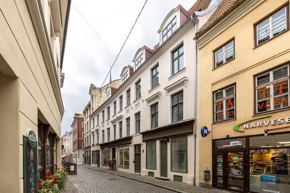 A narrow cobblestone street lined with historic buildings, including a store with a visible sign.