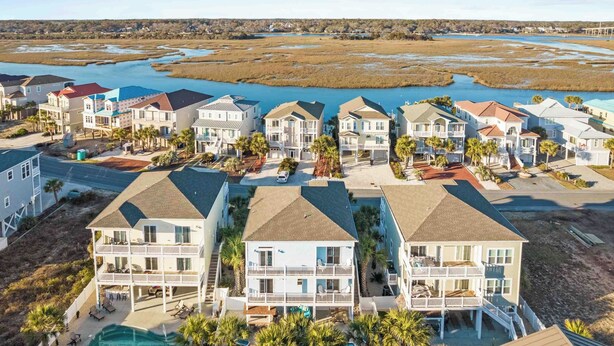 A coastal residential area with multiple two-story houses, a swimming pool, and a view of a marshy landscape with a river. - Sonrise 5-bedroom, 5.5-bathroom home w/ private pool, ~4 mins to the beach! (Ocean Isle Beach)