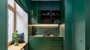 Una cocina compacta con armarios verdes, horno integrado y ventana con vistas.