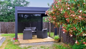 A covered outdoor seating area with wicker furniture and a wooden deck.