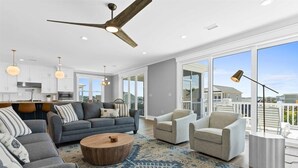 A spacious living room with a gray sofa, a round coffee table, and a large window offering a view of the outdoors.