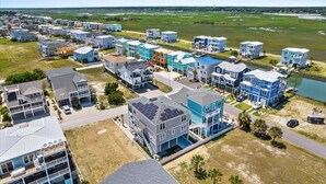 A residential area with modern houses, a road, and a body of water in the background.