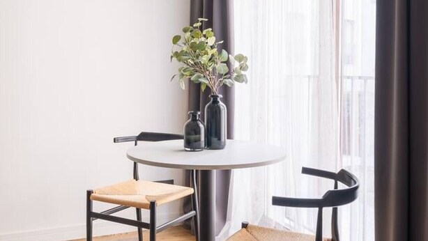 A modern dining area with a round table, two chairs, and hanging pendant lights.