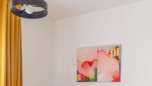 Um sofá cor turquesa em um quarto com piso de madeira, uma cortina amarela e um quadro pendurado na parede.