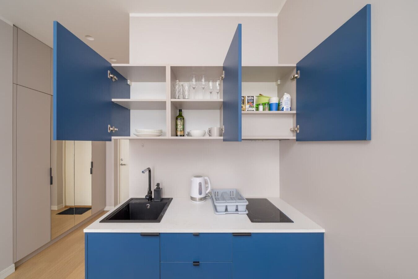 Een koelkast, een kookplaat, kookgerei, borden en bestek, eettafels