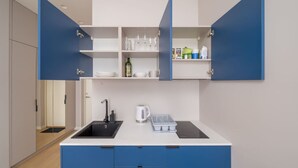 Una cocina moderna con armarios azules, un lavamanos, un hervidor y una encimera.