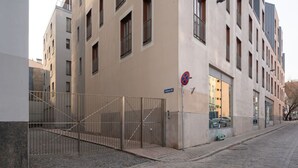 Vista de la calle con un edificio que tiene un acceso porticado, un cartel de no estacionamiento y pavimento adoquinado.