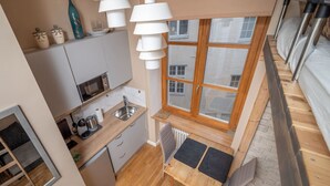 Una cuina compacta amb finestra, zona de dinar i taula petita amb cadira.