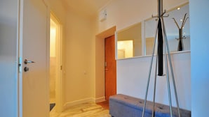 Un couloir avec un plancher en bois, un banc bleu et un miroir accroché au mur.