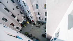 A high-angle view of a narrow urban courtyard with buildings on either side, featuring a staircase leading down to a lower level. - Lacplesa loft-style residence (Riga)