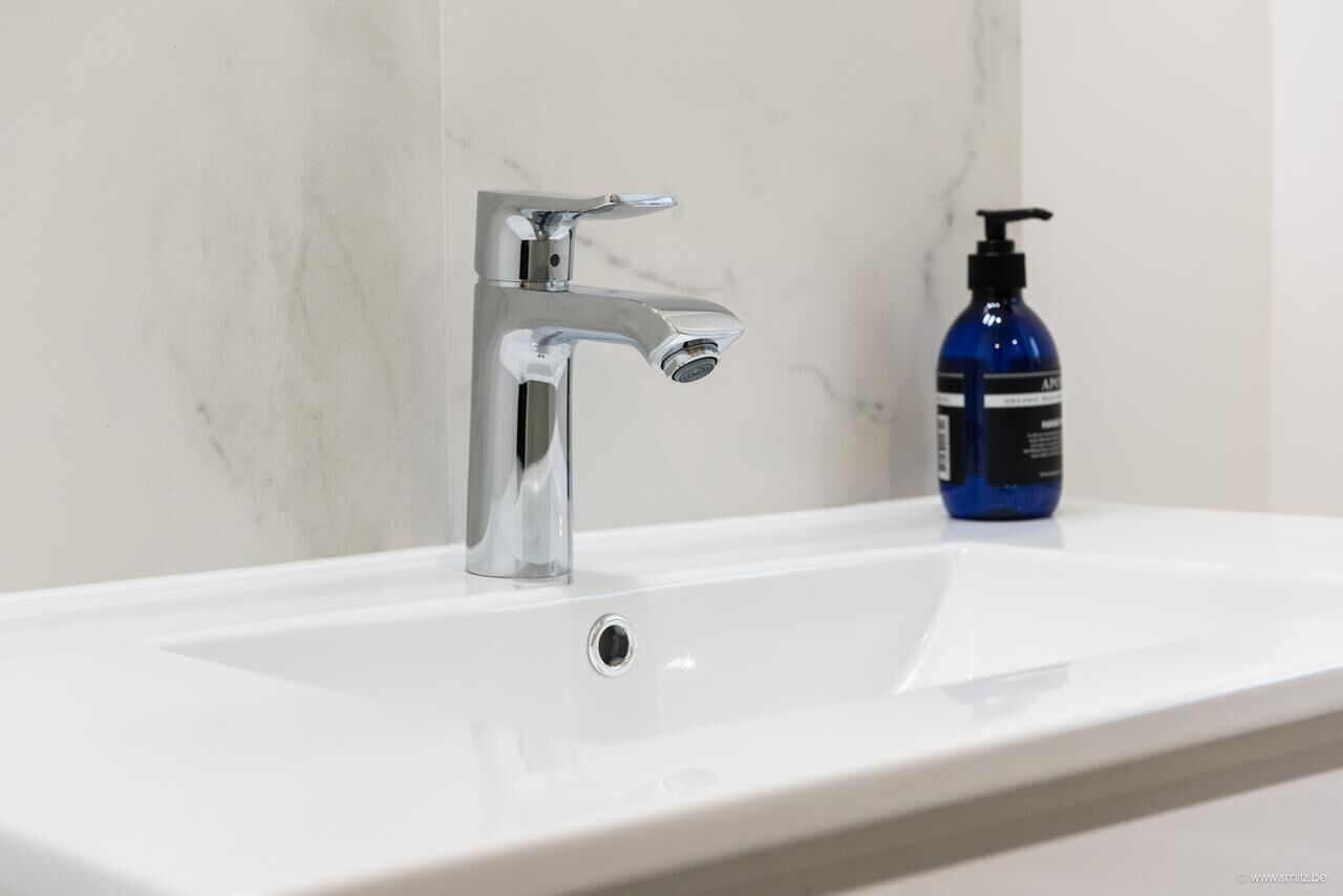 A bathroom with a chrome faucet and a white sink.
