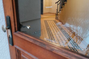 Un pasillo con baldosas estampadas y una puerta de madera.