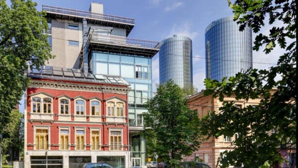 Ein historisches Gebäude mit roter Fassade und einer modernen Glasarchitektur im Hintergrund.