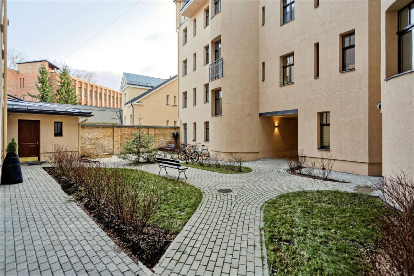 A courtyard with a paved walkway, a bench, and a bicycle.
