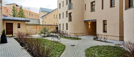 A courtyard with a paved walkway, a bench, and a bicycle.