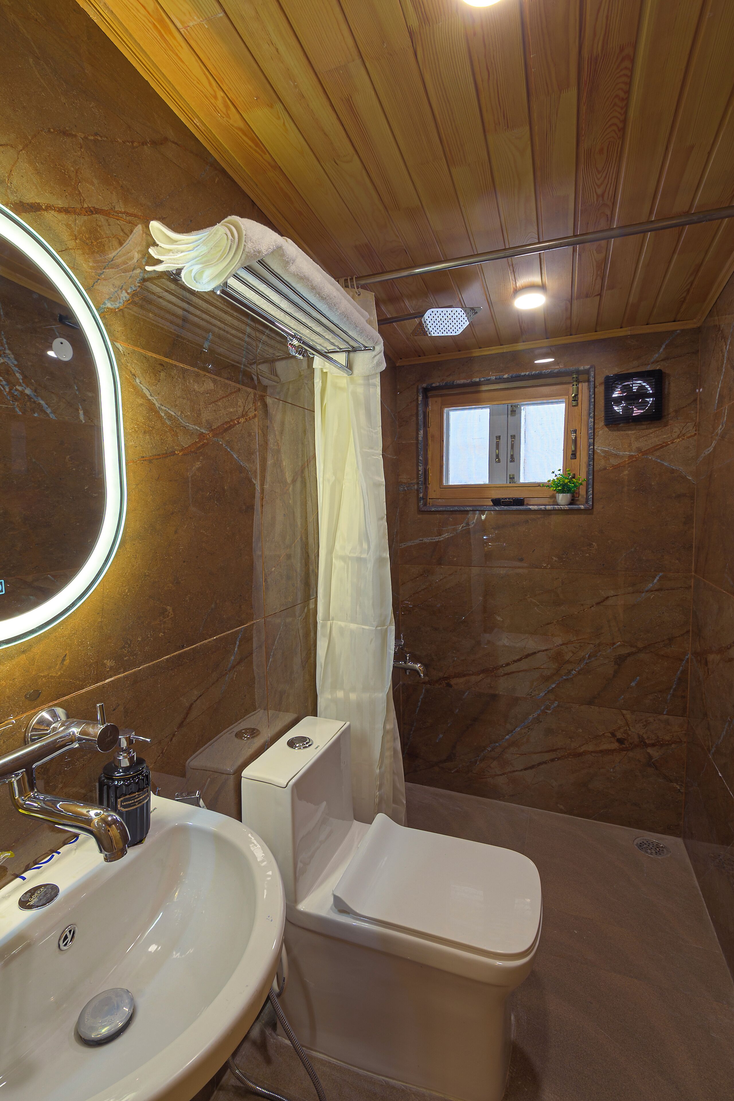 A bathroom with a sink, toilet, and a small window.