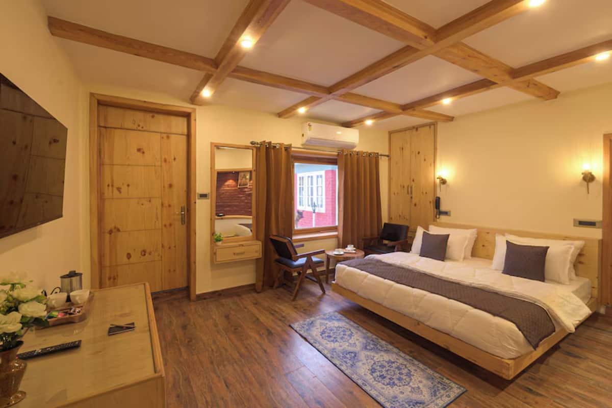 A bedroom with a bed, a desk, a chair, a mirror, and a window with curtains.