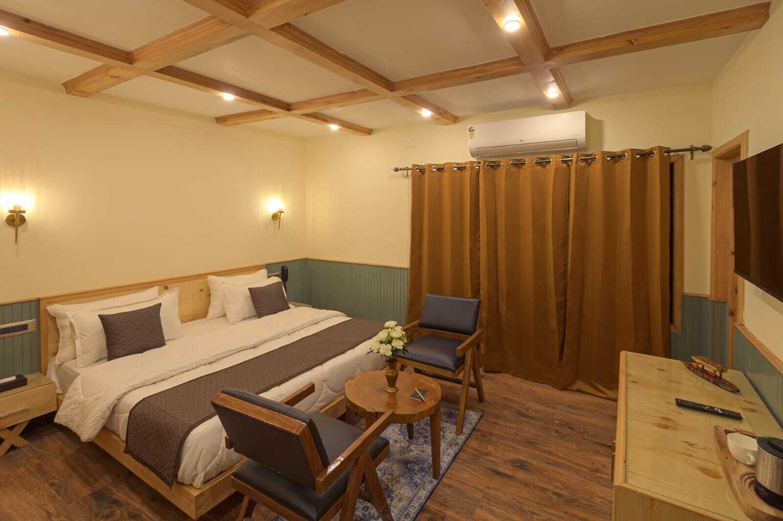 Un dormitorio con una cama doble, dos sillas, una mesita y un equipo de aire acondicionado.